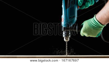 Drilling wooden plank, closeup black background textplace.