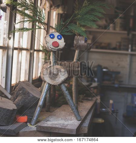 Dark toned photo: making wooden reindeer from the logs in the shed; unfinished wooden deers selective focus