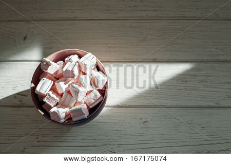 Marshmellow in purple bowl on a wooden background. Top view. The concept of food.