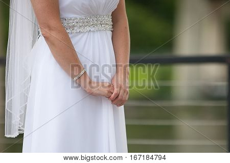 A bride with folded hands stands waiting