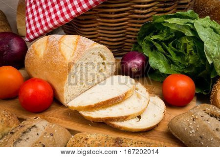 Picnic spread with basket bread red tomatoes green lettuce and red spanish onion still life