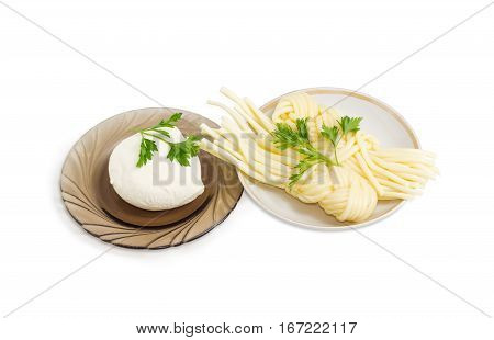 Ball of the fresh soaked mozzarella cheese on the glass saucer two portions of the mozzarella cheese twisted to form a plait on the other saucer and twigs of parsley on a light background
