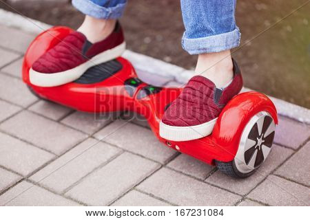 Feet of a gir in marsala shoes riding on modern red electric mini segway or hover board scooter. Trending new transportation technology that is so much fun and easy to ride and produces no air pollution to the atmosphere. Focus on the device