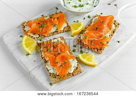 Homemade Crispbread toast with Smoked Salmon, Melted Cheese and cress salad. on white wooden board.