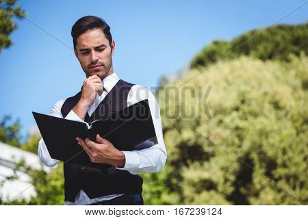 Handsome waiter looking at the menu outside