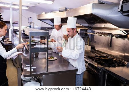 Group of chef preparing food for client in commercial kitchen
