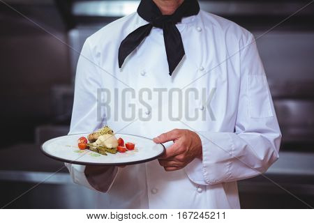 Proud chef holding a plate in a restaurant