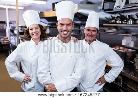 Group of happy chefs in uniform smiling at the camera in a kitchen