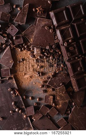 Chocolate chunks and cocoa powder. Coffee beans Chocolate bar pieces. Large bar of chocolate on gray abstract background. Background with chocolate. Slices of chocolate. Sweet food photo concept.