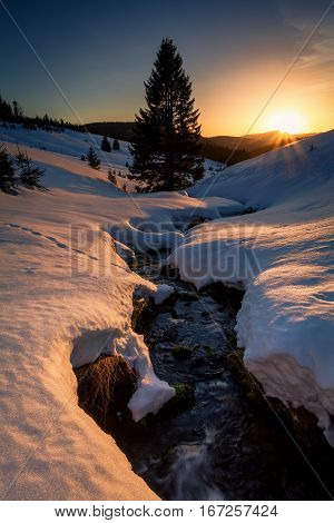last sunrays over mountains river in snowy winter
