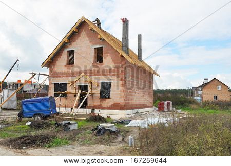 Roofer Install and Repair Asphalt Shingles or Bitumen Tiles on the Rooftop. Building New House from Ceramic Blocks and Roofing Construction Exterior. House Construction Site View Outdoor.