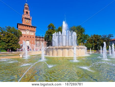 MILAN ITALY - September 07 2016: View on the Fountain of Piazza Castello ( Piazza Castello Springbrunnen) and the Tower with clock of Castello Sforzesco in Milan Italy