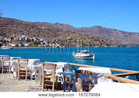 ELOUNDA, CRETE - SEPTEMBER 17, 2016 - Restaurant tables on the waterfront with views across the bay Elounda Crete Greece Europe, September 17, 2016.