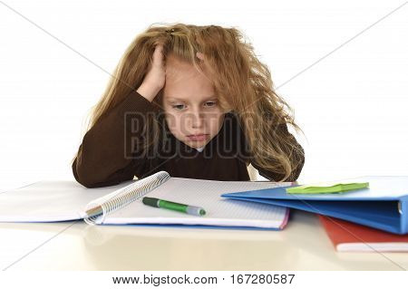 sweet little schoolgirl sad and tired looking depressed suffering stress overwhelmed by load of homework and schoolwork on desk with notepad and pen in school child performance concept