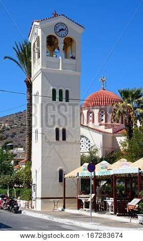 ELOUNDA, CRETE - SEPTEMBER 17, 2016 - Clock tower with a Greek church to the rear in the town centre Elounda Crete Greece Europe, September 17, 2016.