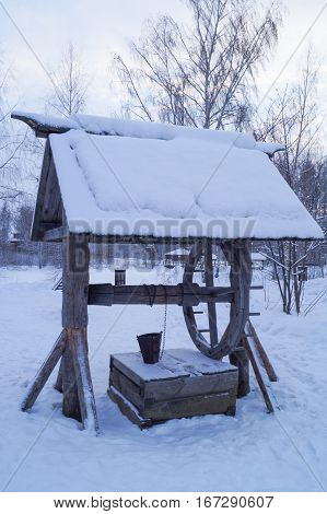 Wooden well in winter village in winter snowy day