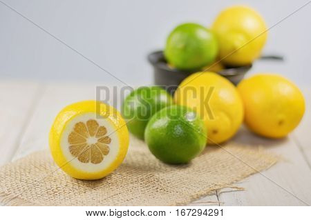 Group of lemons and limes with a small bowl in the background.