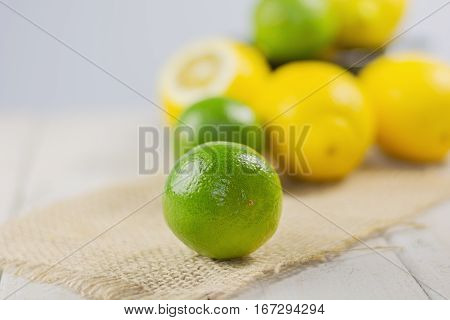 Group of lemons and limes with a small bowl in the background.