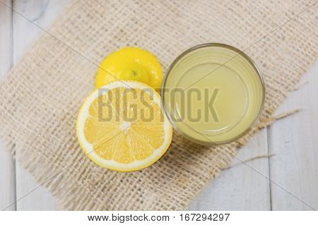 A glass of squeezed lemon juice and lemons around.