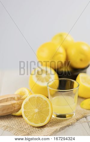 A glass of squeezed lemon juice and lemons around.