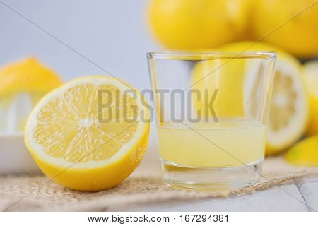 A glass of squeezed lemon juice and lemons around.