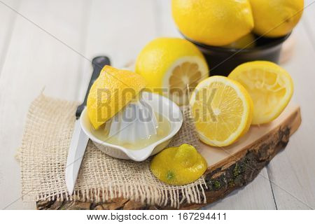 Juicer for lemon on a wooden plank and cut and whole lemons around.