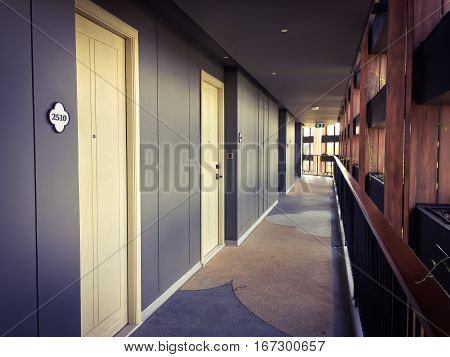 Corridor in hotel building with apartment rooms and windows grey walls and beige doors