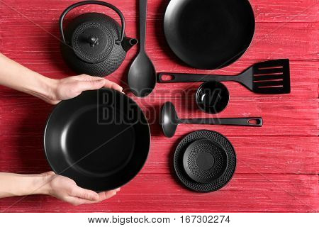Female hands and dishware on red wooden background