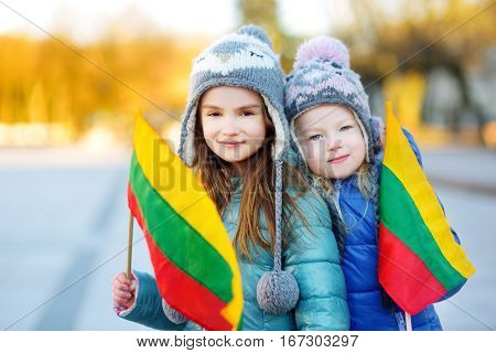 Two Adorable Little Sisters Celebrating Lithuanian Independence Day Holding Tricolor Lithuanian Flag