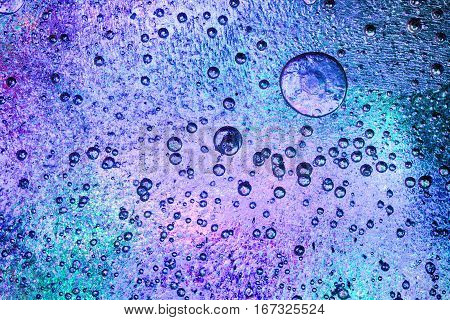 Frozen ice crystals with beautiful pink and blue colours below. Large and small trapped air bubbles all across the ice.