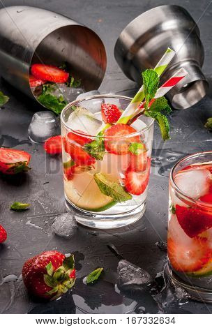 Summer refreshing mojito cocktail with strawberry mint and lime on a dark gray stone (concrete) table with shaker for whipping drinks