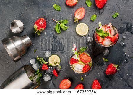 Summer refreshing mojito cocktail with strawberry mint and lime on a dark gray stone (concrete) table with shaker for whipping drinks top view