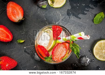 Summer refreshing mojito cocktail with strawberry mint and lime on a dark gray stone (concrete) table with shaker for whipping drinks top view