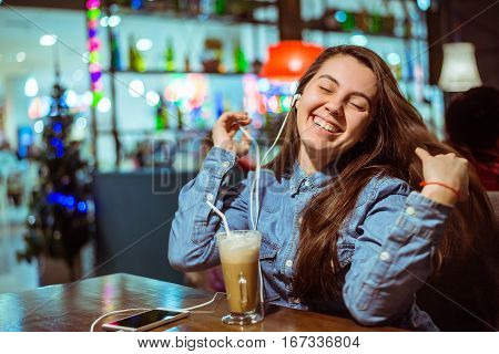Music smartphone in female hand, on cafe interior background, injoy