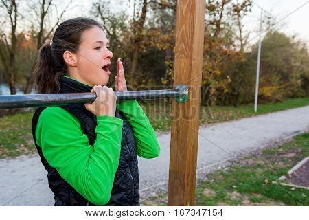 Young athlete effortlessly doing one-hand pullups. Outdoor fitness.