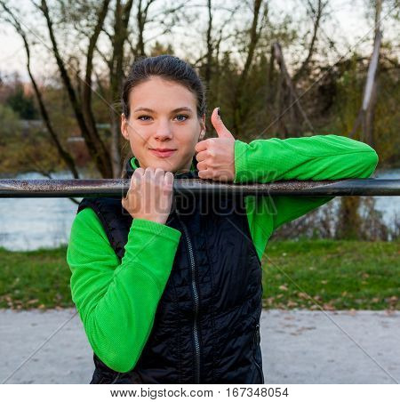 Young athlete giving thumbs up while doing pullups. Outdoor fintess.