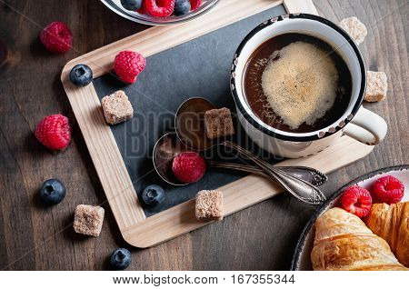 Coffee croissants with raspberries and bluererries for breakfast. Toned image selective focus top view