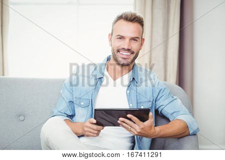 Portrait of cheerful man holding digital tablet at home