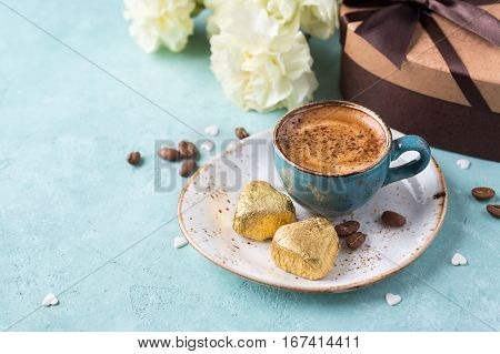 Coffee mug with yellow and chocolates on blue rustic table from above. Valentine's Day background or Womens day