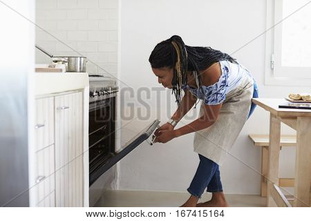 Woman bending down to look into the oven in her kitchen
