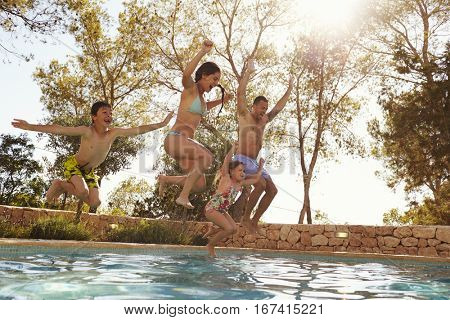 Family On Vacation Jumping Into Outdoor Pool