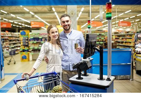 shopping, sale, payment, consumerism and people concept - happy couple with credit card buying food at grocery store or supermarket self-service cash register