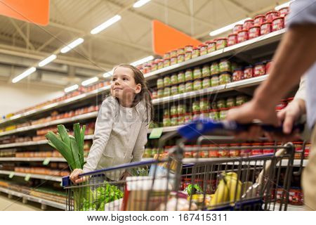 family, sale, consumerism and people concept - happy child and father carrying shopping cart buying food at grocery store