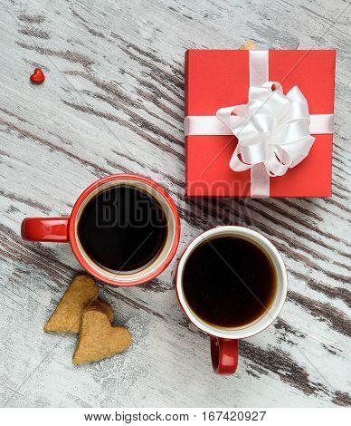 two red coffee cup, hearts cokies and gift box on wooden surface. Valentines day concept.