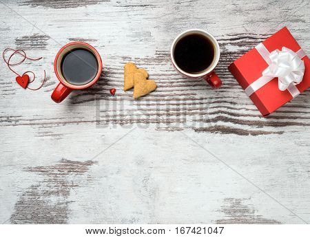 two red coffee cup, hearts cokies and gift box on wooden surface. Valentines day concept.