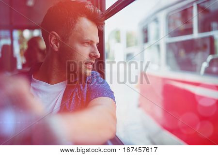 Close up of handsome man looking through window while traveling in bus