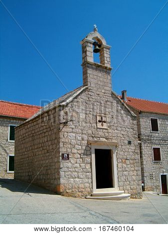 Photo of an old stone chaple surrounded by buildings
