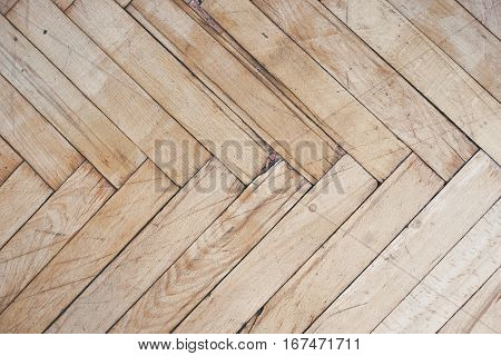 Close top view on rich texture of old brushed and distressed wooden parquet floor made from many racks in herringbone pattern, abstract background image