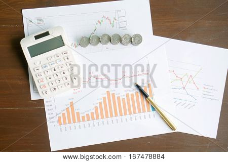 Calculator coins and pen laying on chart. Concept of finance.