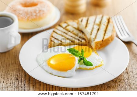 Breakfast with fried eggs coffee and dessert on table. Healthy food